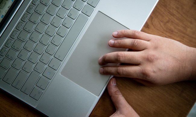 A pair of hands using a keyboard on a laptop.
